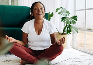 Senior woman smiling while meditating at home