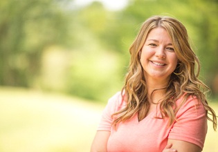 Woman in pink shirt smiling outside