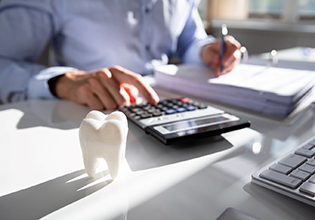 A fake tooth in front of a businessperson calculating a bill