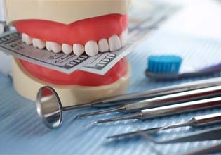 Dental model holding money next to dental instruments
