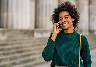 Woman smiling while talking on phone outside