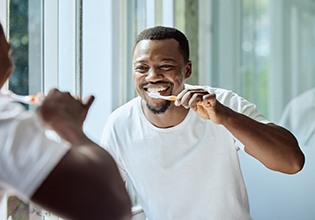 Man smiling while brushing his teeth