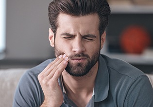 Man holding cheek in pain