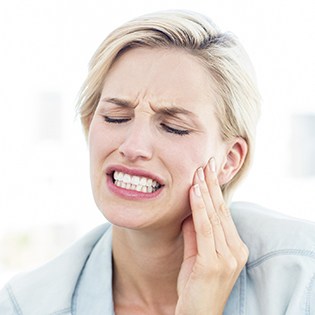 Woman holding cheek in pain