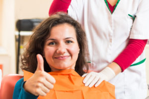 Woman in dental chair giving thumbs up