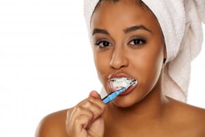 young woman smiling while brushing her teeth