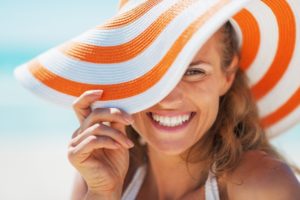 Smiling woman in sun hat with porcelain veneers near Palmer