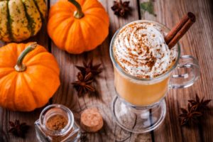 PSL with whipped cream on table with pumpkins