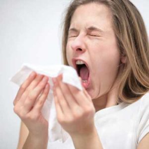 Woman sneezing into tissue