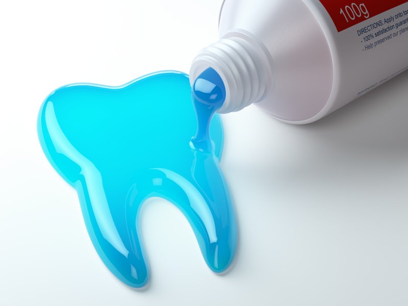 Open toothpaste tube pouring blue fluoridated toothpaste into the shape of a tooth