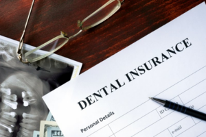A form that says dental insurance sitting on a desk next to a dental X-ray