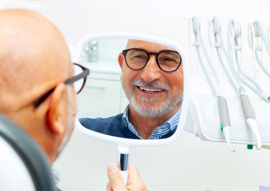 A man looking in the mirror at his new dental implants